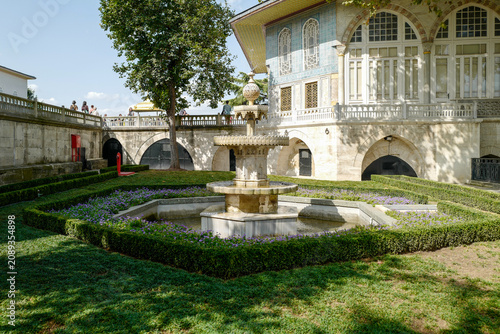 Bild auf Leinwand Classical multi-tiered fountain in the sunlit Topkapi Palace gardens, surrounded by a symmetrical lavender parterre and backed by the iconic blue-tiled Ottoman pavilion
