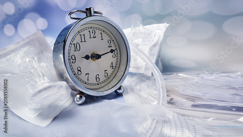 An old alarm clock against the backdrop of male silicone catheters