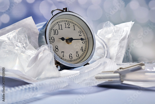 an old alarm clock surrounded by male silicone catheters