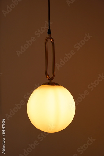 a round decorative lamp that is lit and is a yellowish-orange colour
