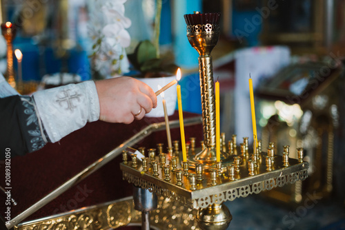 A person's hand lighting a candle in a church, side view.