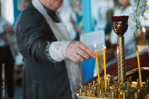 A person's hand lighting a candle in a church, side view.