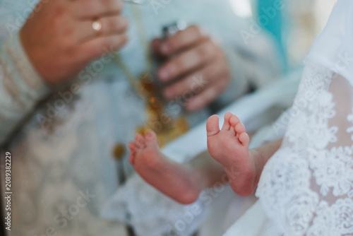 Legs, feet, baby close-up, during the baptism ceremony.