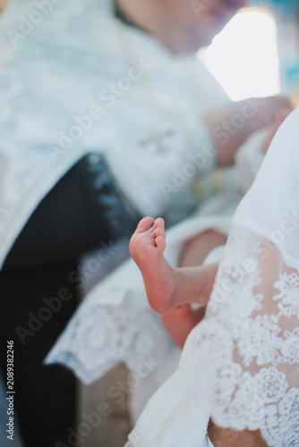 Legs, feet, baby close-up, during the baptism ceremony.
