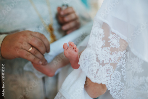 Legs, feet, baby close-up, during the baptism ceremony.