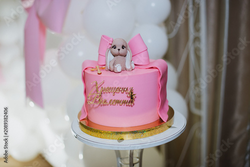 Pink cake with a bunny for a girl, baptism, on a white background.