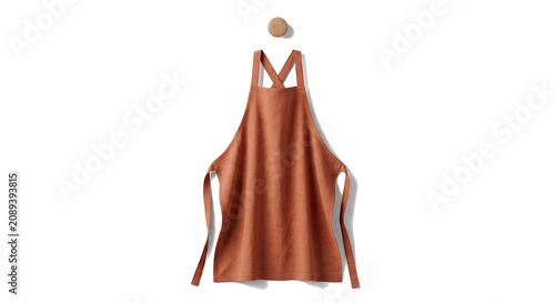 A stylish orange apron hangs on a wooden hook on the wall.