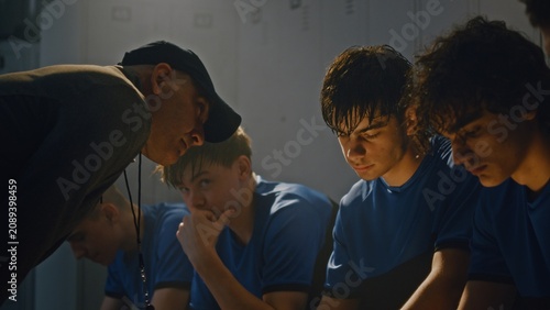Middle Aged Sports Coach Lecturing Youth Soccer Team in Locker Room. Team Sits Quietly on Benches, Processing Harsh Feedback. High Stakes, Tension, and Emotional Weight of Competitive Youth Sports.