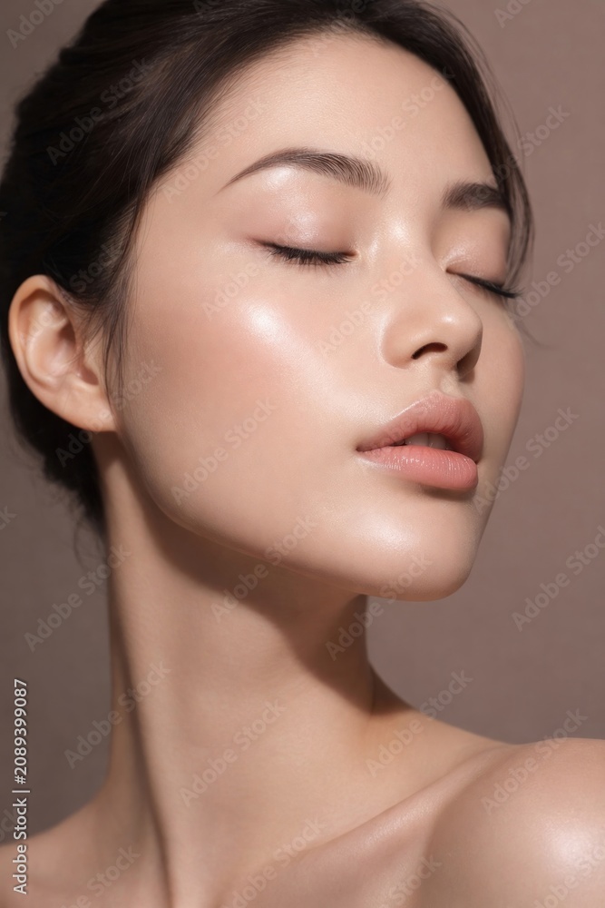 Obraz premium Close-up of a woman with flawless skin and closed eyes, serene expression.