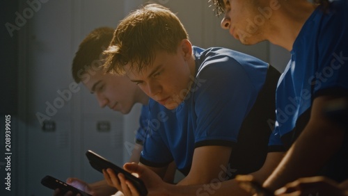 Fotografía Friendly Interaction in Youth Sports Dressing Room Where Group of Teenage Football Players Using Smartphones and Chatting