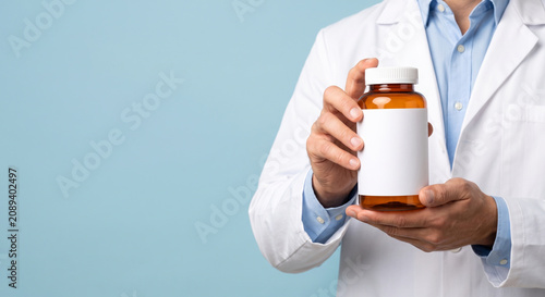 Unrecognizable doctor in medical uniform holding empty transparent brown bottle with copy space.