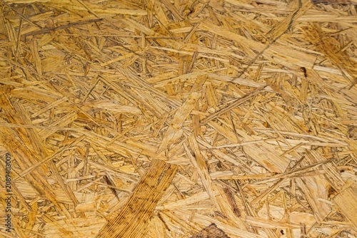 Close-up of a yellow particle board surface showing wood fibers, chips, and subtle texture. Ideal as a modern material background for graphic design projects.