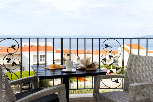 Breakfast table on a balcony overlooking red rooftops and the Adriatic Sea in Makarska, Croatia. Peaceful travel lifestyle scene
