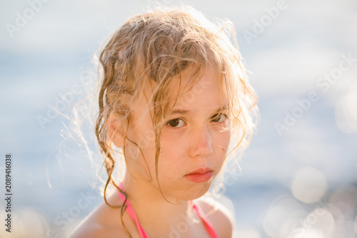 Fotografie Girl aged 7 with wet blonde hair pouts with offended expression in soft bright s
