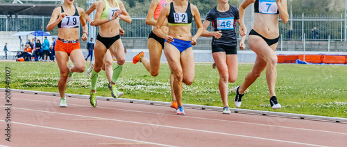 Group female athletes running  800-meter race at stadium