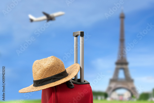 For travel and vacations purposes, a simple modern suitcase in red color and hat in Paris.
