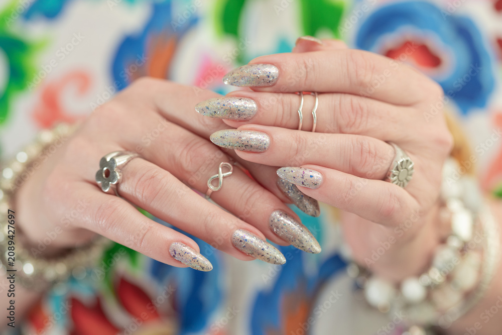 Fototapeta premium Female hand with long nails and a white gray silver manicure