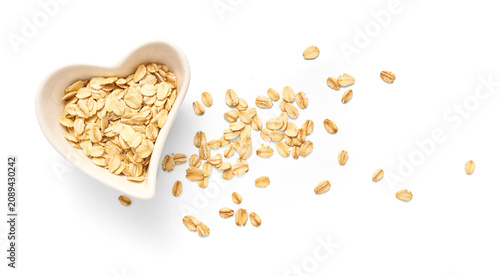 Foto A heart-shaped white bowl brimming with rolled oats, with additional oat flakes