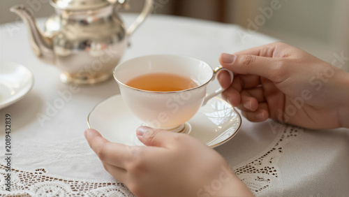 Close-up of a person gently holding an elegant teacup filled with warm tea. This cozy moment suggests relaxation and a luxurious lifestyle, perfect for unwinding