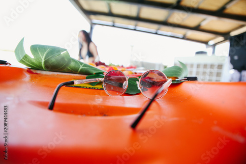 Close Up of Modern Circular Sunglasses Resting on an Orange Kayak During a Sunny Summer Vacation