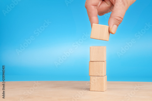 Hand stacking wooden cubes for business growth and development