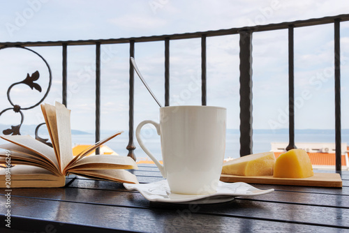 Balcony breakfast with coffee and open book overlooking the Adriatic Sea in Makarska, Croatia.