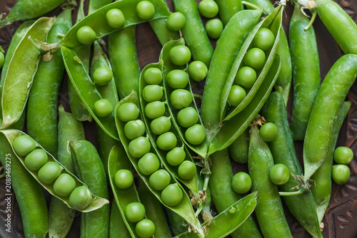 Obraz na plátně Close-up of fresh green pea pods with vibrant peas nestled inside, showcasing natural freshness and healthy seasonal vegetables on a rustic background