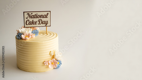 A decorated yellow cake with floral accents and a 'National Cake Day' sign