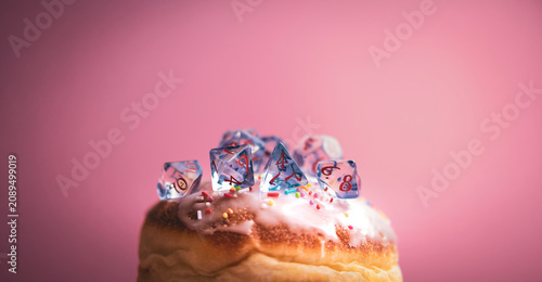 Foto Stock photo of translucent role-playing dice set stick into sweet doughnut with marmalade filling