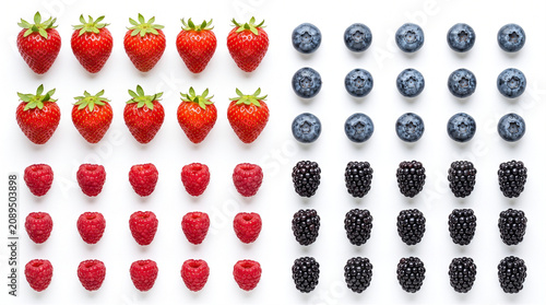 Flat lay grid pattern of fresh strawberries, blueberries, raspberries, and blackberries isolated on white background