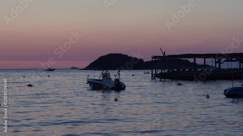 A small motorboat floating on calm waters at sunset along the Albanian Riviera