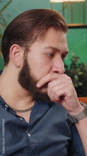Sad lonely man sitting at home room looks pensive thinks over life concerns or unrequited love suffers from unfair situation. Arabian alone boy problem, break up, depressed feeling bad annoyed burnout