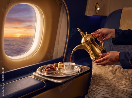 Pouring traditional Arabic coffee in luxury airplane cabin during scenic sunset flight