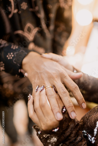 Two hands holding golden wedding rings in elegant gesture