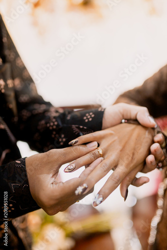 Two hands holding golden wedding rings in elegant gesture