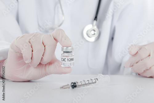 Canvas Print Confident doctor wearing white coat holding liquid peptide vial near plastic inj