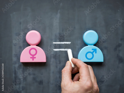 Hand holding condom between male and female symbols on chalkboard, sex education and safe sex concept