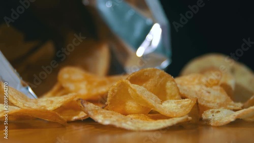 Close-up of a hand picking potato chips, representing unhealthy snacking and junk food habits.