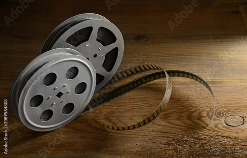 Vintage Metal Movie Reels With Unrolled Film Strip On Old Textured Wooden Table Surface Close Up