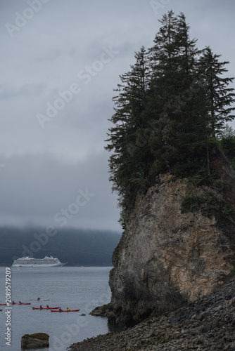 Breathtaking and impressive panoramic scenic view of Icy Strait Point Hoonah, AK coast with lush mountain vegetation and trees during summer Last Frontier cruise with distant mountain range glaciers