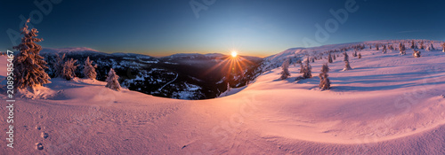Fotografie Vibrant pink and orange alpenglow sky over snow-covered winter mountain ridges, Krkonose