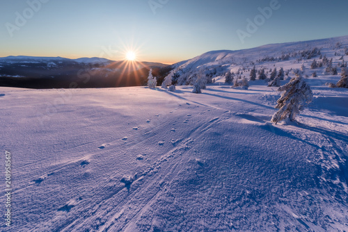 Fotografía Winter sun hanging low over an endless field of untouched white snow on a mountain plateau, Krkonose