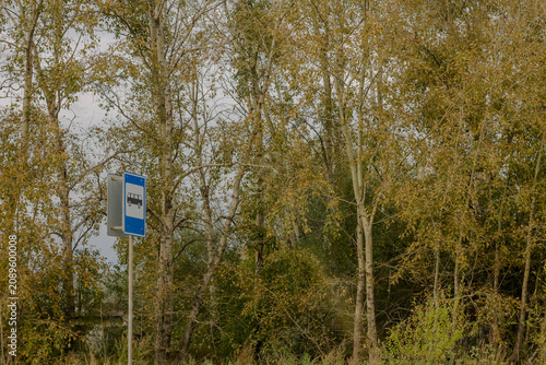 Road sign on the bank of the river with trees in the background