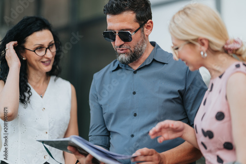 Canvas Print Three business colleagues examine a document together while discussing details