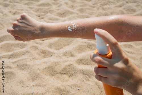 Tableau sur toile using sunscreen before sunbathing on a sandy beach