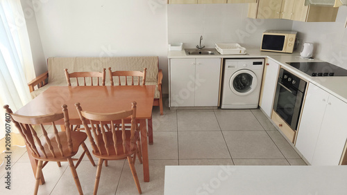 Konstfotografi Bright modern apartment kitchen with dining area, wooden furniture and fully equipped appliances