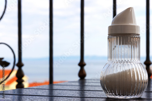 Glass sugar shaker on a balcony breakfast table with Adriatic sea view in Makarska, Croatia