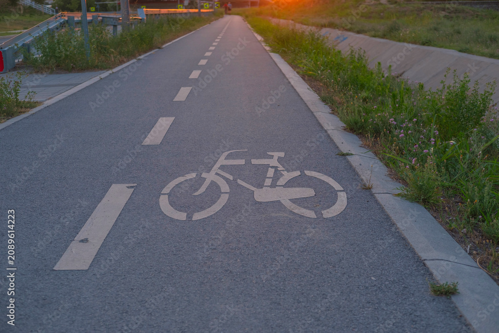 Fototapeta premium Bicycle on a quiet road, lane marking visible under sunset light, urban outdoor scene highlighting cycling, road safety and calm travel