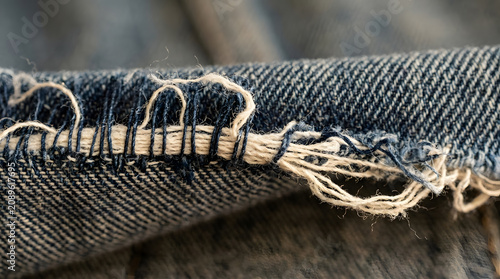 Extreme macro of frayed denim fabric edge showing individual indigo cotton thread texture and warp weave, textile detail