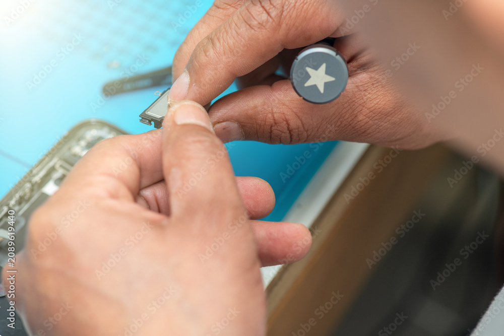 Fototapeta premium Technician repairing smartphone components on a workbench in electronics repair laboratory